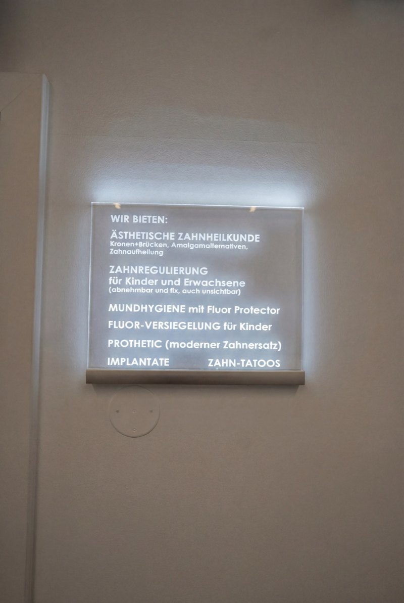 Beleuchtetes Schild mit den Leistungen der Ordination